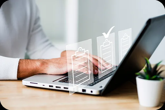 Mains sur le clavier d’un ordinateur portable, des documents validés s’affichent au-dessus