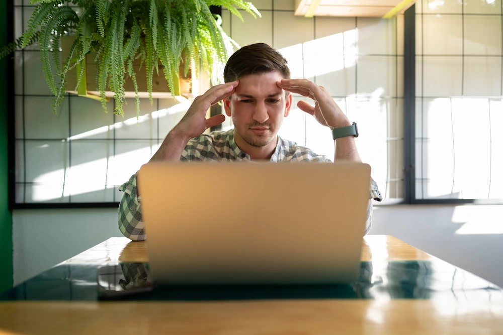 Dirigeant de petite entreprise devant son ordinateur portable, la tête dans les mains