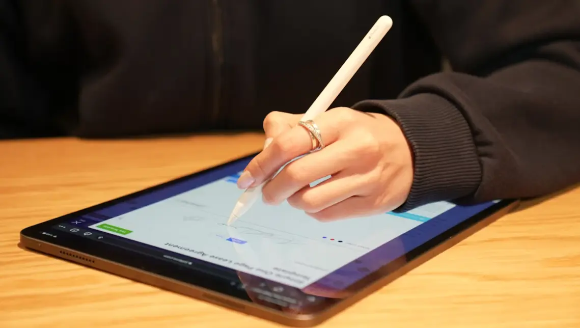 Main qui signe un document au stylet sur une tablette